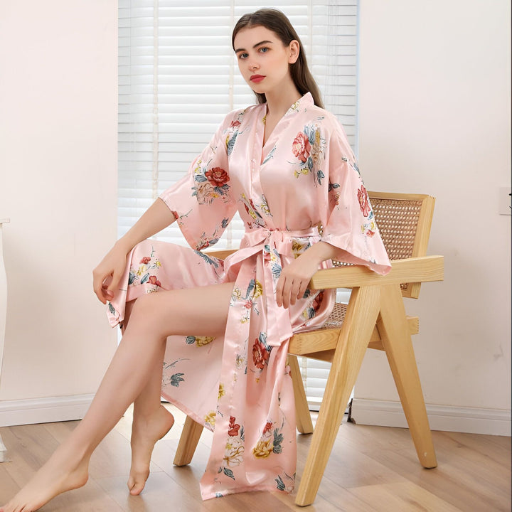 Femme assise sur une chaise en kimono rose à fleurs. Peignoir de style japonais, parfait pour la détente à la maison. Vente de kimonos en ligne.