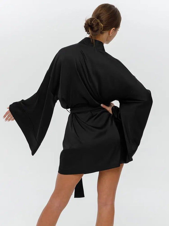 Femme portant un kimono noir élégant, vue de dos. Manches amples et ceinture assortie. Découvrez notre collection de kimonos de qualité supérieure pour un style unique.