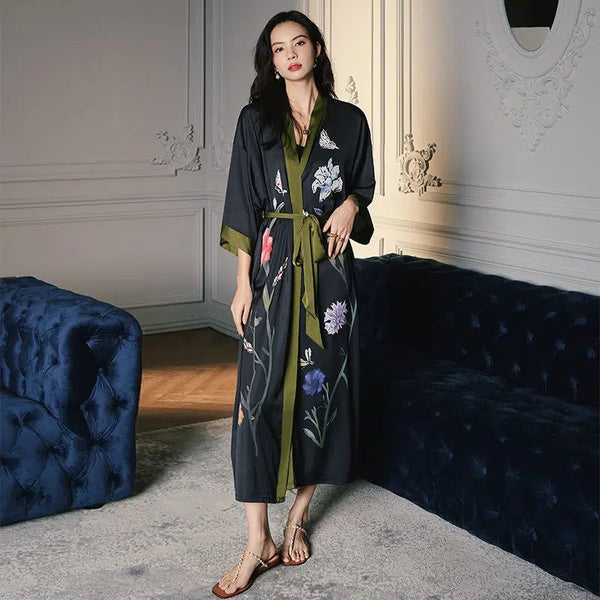 Femme portant un kimono noir à motifs floraux et papillons, avec une ceinture verte. Kimono élégant et confortable à vendre.