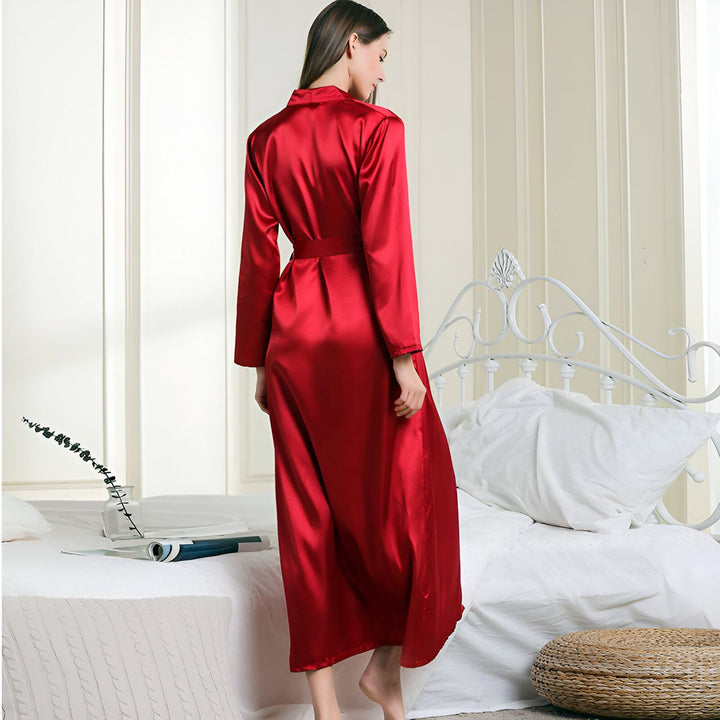 Femme portant un kimono rouge en satin long avec une ceinture. Vêtements de nuit confortables et élégants. Idéal pour la détente à la maison. Kimono de qualité disponible à l'achat.