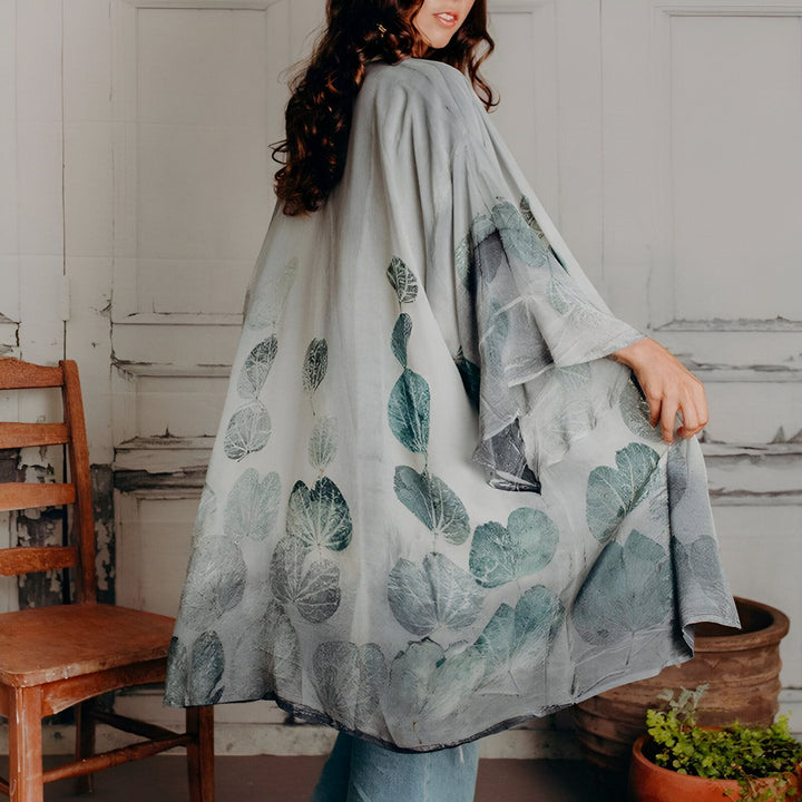 Femme portant un kimono à motifs de feuilles bleues et grises. Vêtements de style kimono, idéal pour un look bohème et élégant. Découvrez notre collection de kimonos uniques.