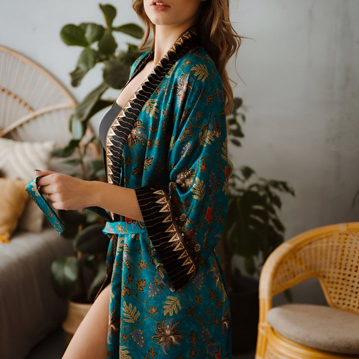 Femme portant un kimono turquoise à motifs floraux, bordure noire, et ceinture assortie. Kimono pour femmes, vente de kimonos en ligne.