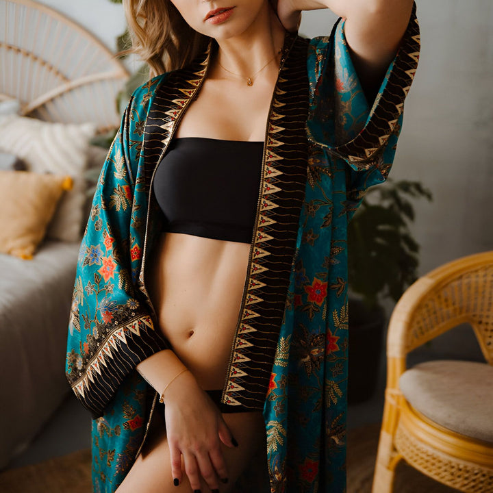 Femme portant un kimono turquoise et noir avec des motifs floraux colorés. Vente de kimonos en ligne.