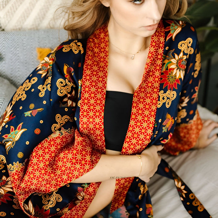 Femme portant un kimono bleu marine et rouge avec motifs floraux. Vêtements de style japonais, kimono élégant et confortable. Idéal pour la détente à la maison ou comme vêtement d'extérieur unique. Découvrez notre collection de kimonos.