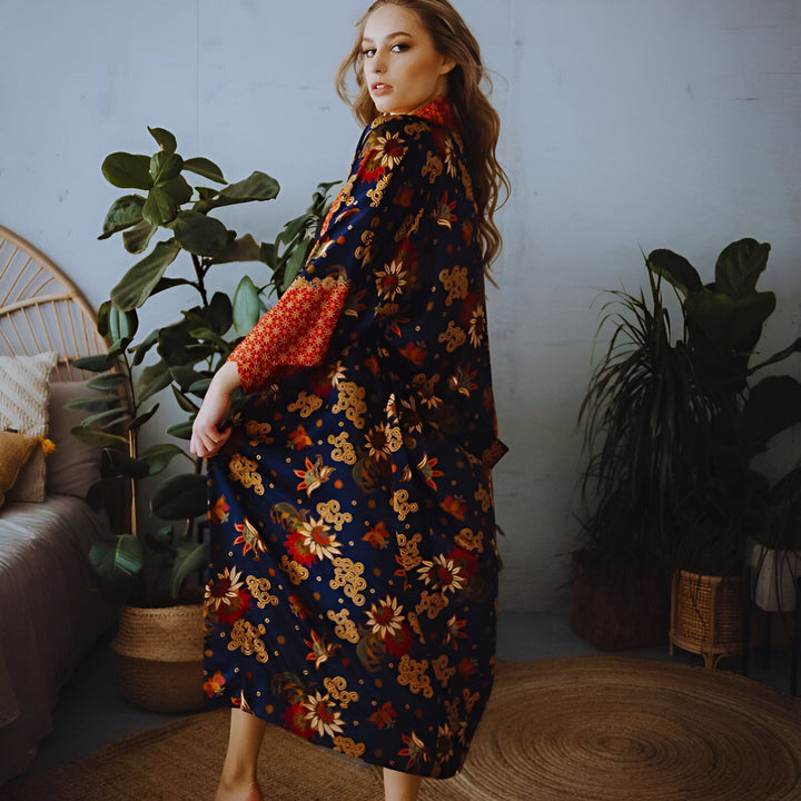 Femme portant un kimono long bleu marine à motifs floraux. Kimono élégant, parfait pour la maison ou les sorties. Découvrez notre collection de kimonos uniques.