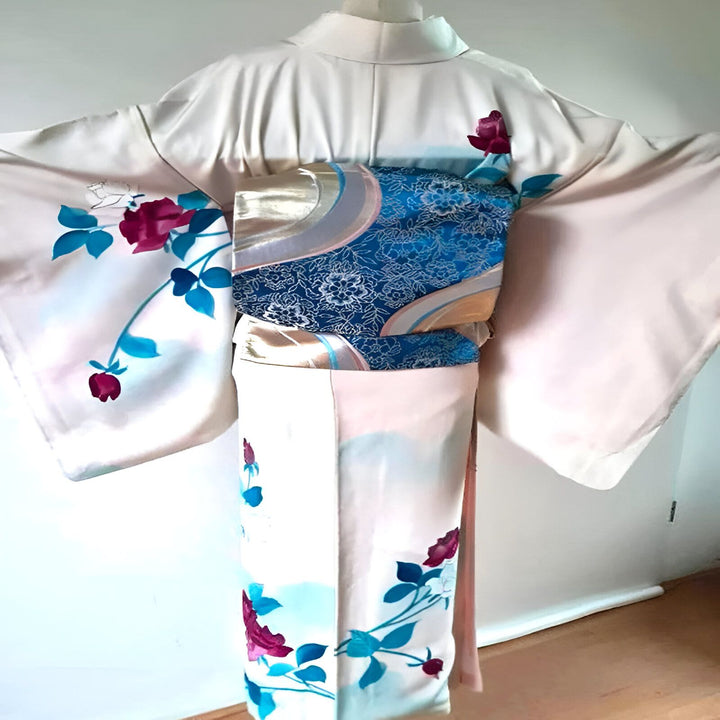 Vue arrière d'un kimono blanc orné de motifs floraux rouges et bleus. Un obi bleu et doré complète la tenue. Découvrez notre collection de kimonos uniques.
