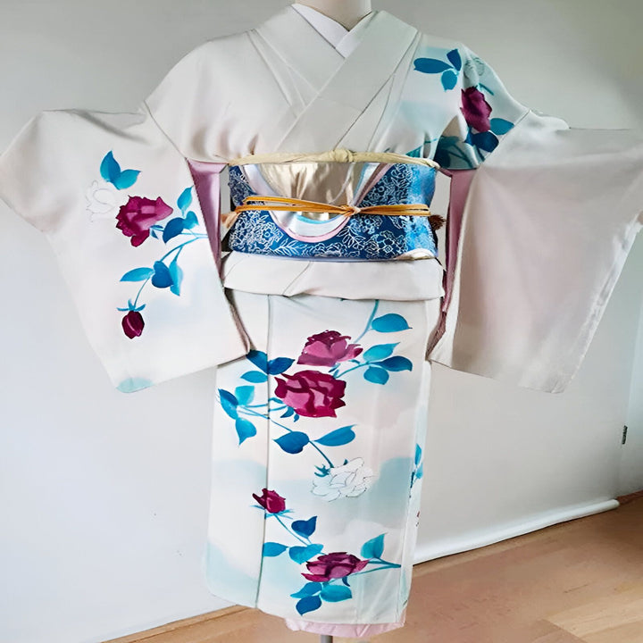 Kimono blanc orné de motifs floraux roses et bleus. Obi décoratif bleu et doré. Vêtements traditionnels japonais.