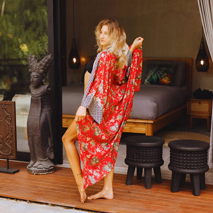 Femme portant un kimono rouge à motifs floraux. Kimono élégant et confortable, idéal pour la détente à la maison ou en voyage. Découvrez notre collection de kimonos uniques.