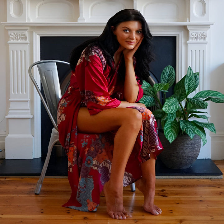 Femme assise portant un kimono rouge fleuri. Vente de kimonos en ligne. Détails élégants et confortables. Mode japonaise revisitée.