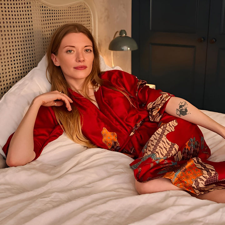 Femme rousse portant un kimono rouge à motifs dans un lit. Vêtements de détente confortables. Kimonos de luxe en vente.