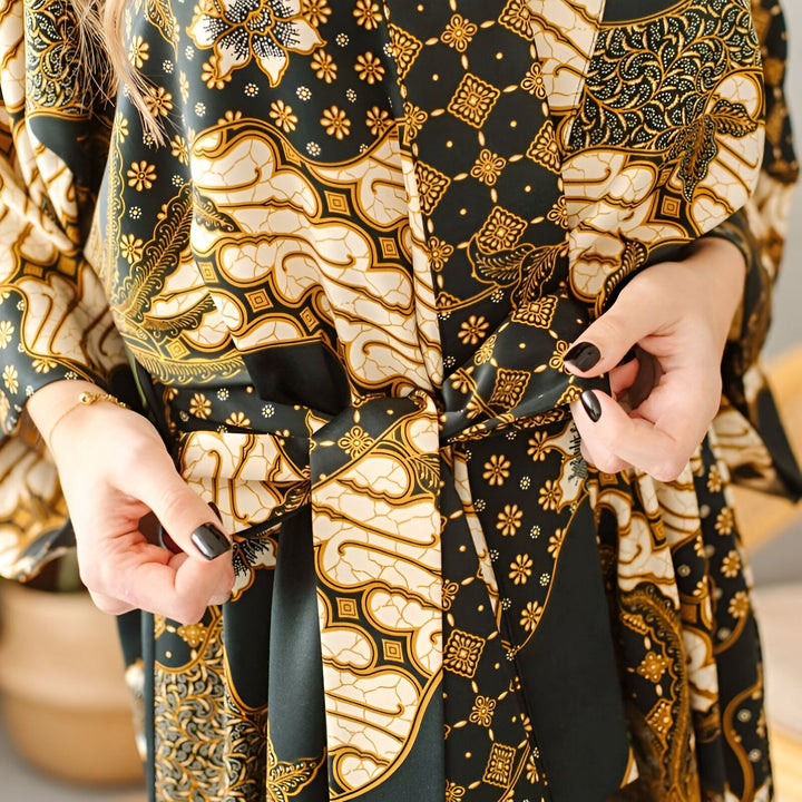 Kimono à motifs complexes noir, or et crème. Détail du nœud de la ceinture. Découvrez nos kimonos élégants.