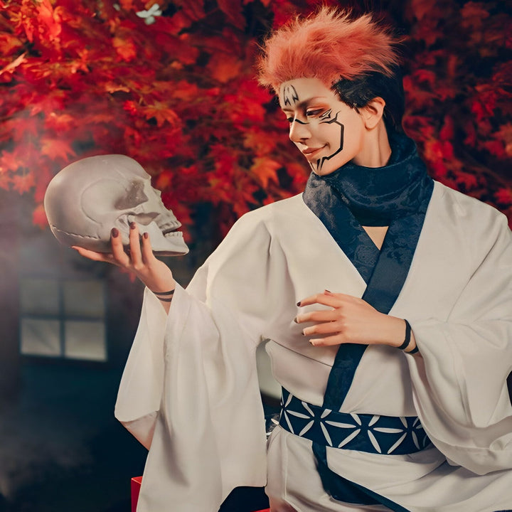 Cosplay d'un homme en kimono blanc tenant un crâne. Maquillage artistique sur le visage. Kimonos traditionnels japonais à vendre. Arrière-plan avec des feuilles d'automne rouges.