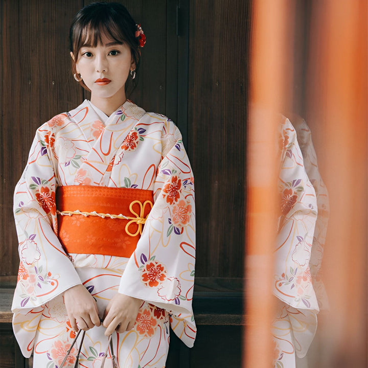 Femme portant un kimono blanc à motifs floraux et une ceinture orange. Vêtements traditionnels japonais.