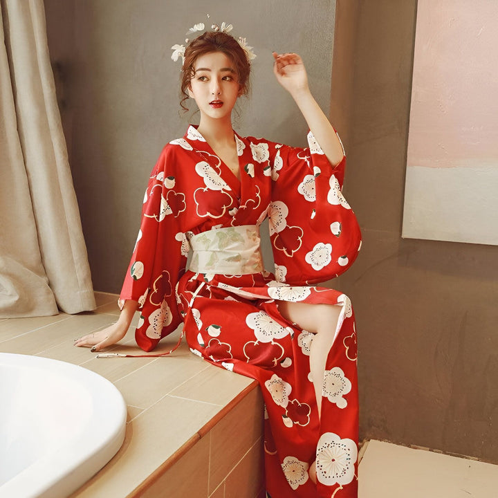 Femme en kimono rouge à motifs fleuris blancs, assise. Vente de kimonos.