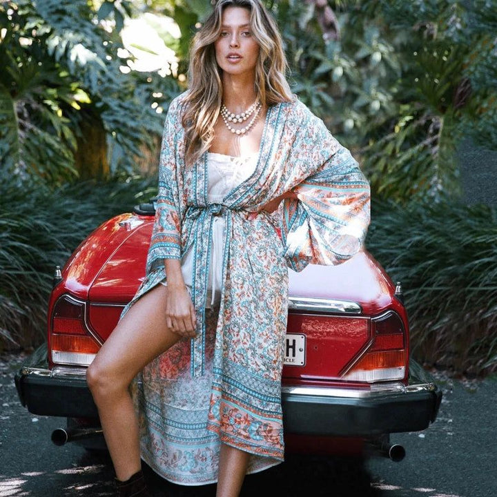 Femme élégante portant un kimono fleuri avec une voiture rouge vintage. Collection de kimonos tendance et confortables pour un style bohème chic.