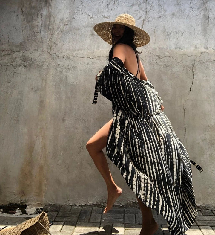 Femme portant un kimono noir et blanc à rayures, chapeau de paille. Vente de kimonos élégants et confortables. Mode kimono.