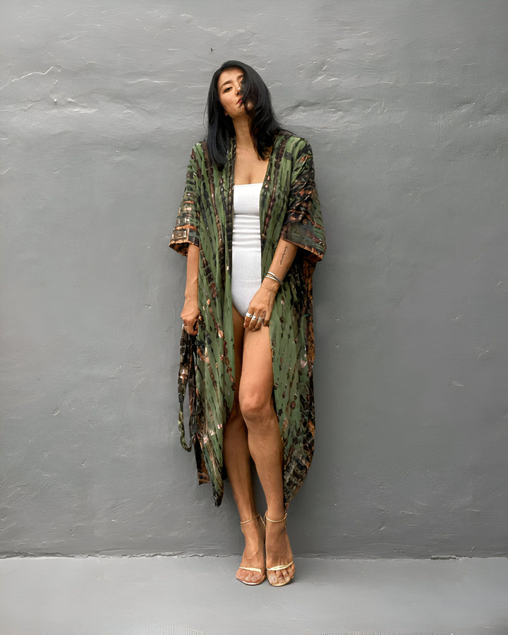 Femme portant un kimono long imprimé vert et marron, avec un maillot de bain blanc et des talons dorés. Vêtements de style kimono à la mode.