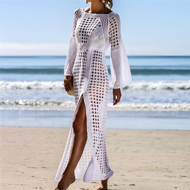 Femme portant un kimono de plage blanc ajouré avec une fente sur le côté, sur une plage ensoleillée. Idéal comme vêtement de plage chic. Découvrez notre collection de kimonos.