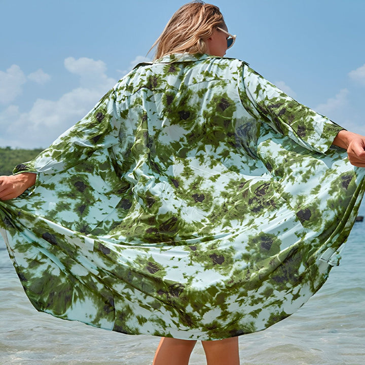 Femme vue de dos portant un kimono tie-dye vert et bleu sur la plage. Kimono ample et fluide. Idéal pour la plage ou une tenue décontractée.