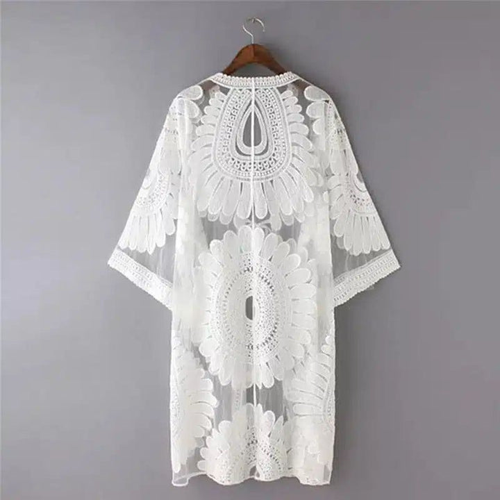 Kimono blanc en dentelle à motifs floraux, suspendu à un cintre. Vêtements de plage chics.