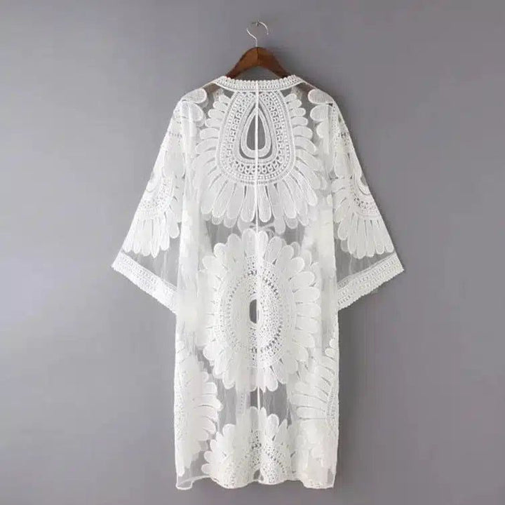 Kimono blanc en dentelle délicate sur un cintre. Idéal pour un look bohème chic. Découvrez notre collection de kimonos.