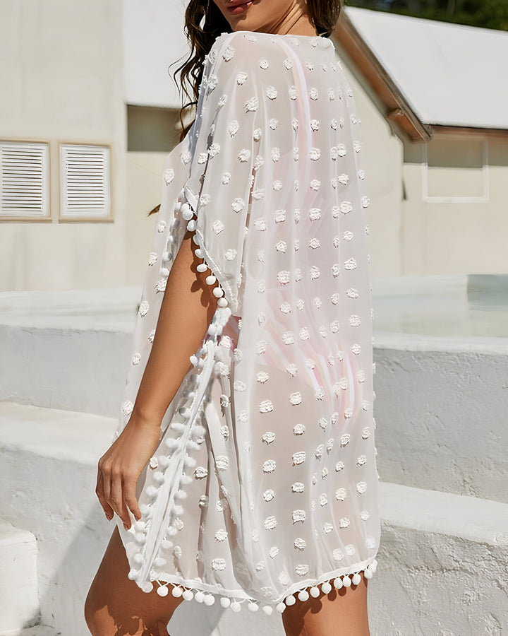 Kimono blanc transparent à pompons. Vêtement léger parfait pour la plage ou la piscine. Idéal pour un look estival chic et décontracté. Notre collection de kimonos offre un style unique et tendance.