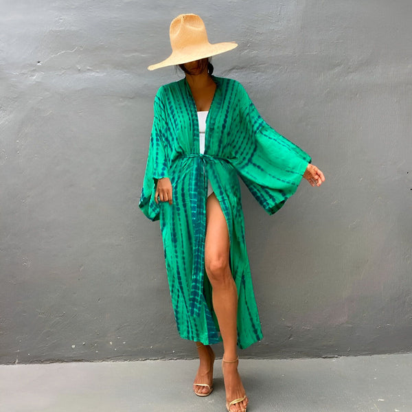 Femme portant un kimono long vert tie-dye avec un chapeau de paille. Vêtements de plage, robe d'été. Kimonos élégants et confortables pour toutes les occasions. Notre collection de kimonos uniques.