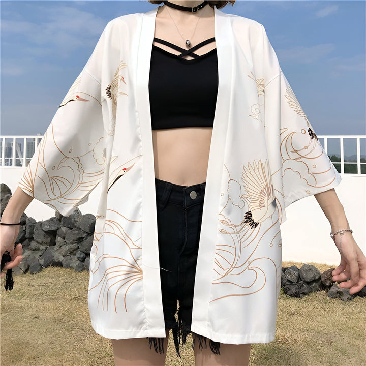 Femme portant un kimono blanc avec motifs de grues. Kimono japonais élégant, parfait pour un look tendance. Découvrez notre collection de kimonos uniques.