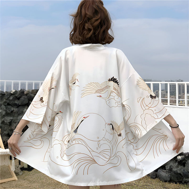 Dos d'une femme portant un kimono blanc à motifs de grues et vagues dorées. Kimono japonais traditionnel, vêtement style kimono.