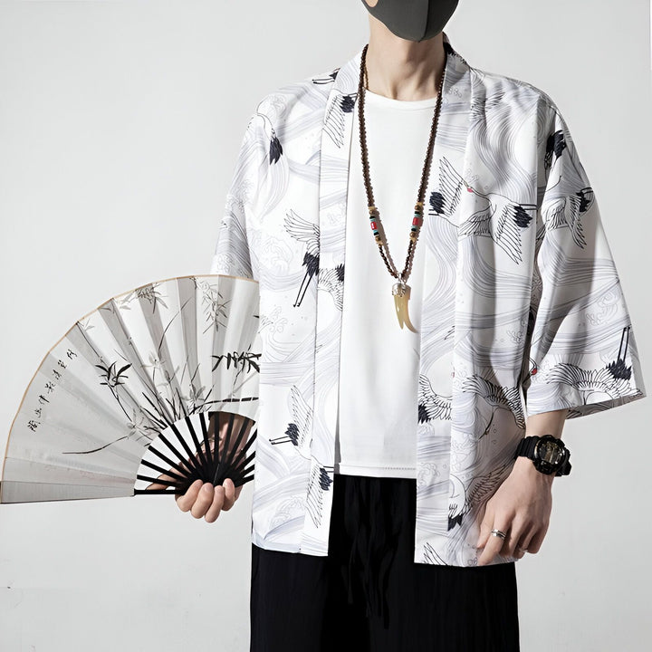 Homme portant un kimono blanc à motifs de grues avec un éventail. Vêtements style japonais. Notre collection de kimonos pour hommes.