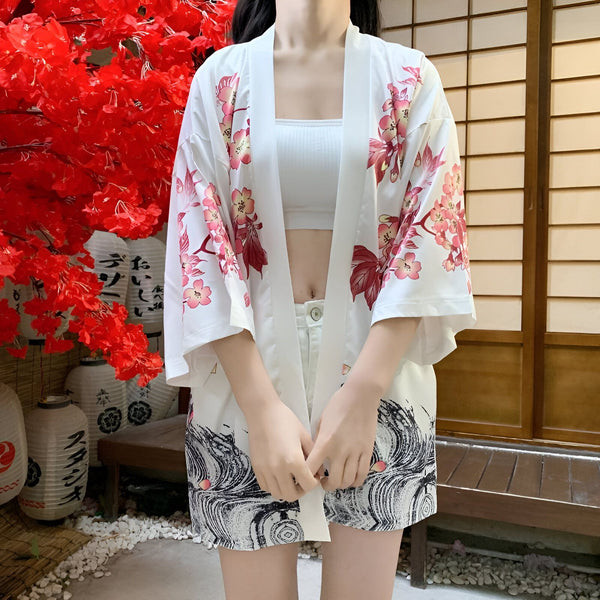 Femme portant un kimono blanc à motifs floraux et vagues japonaises. Kimono léger et élégant, idéal pour l'été. Vente de kimonos traditionnels et modernes.