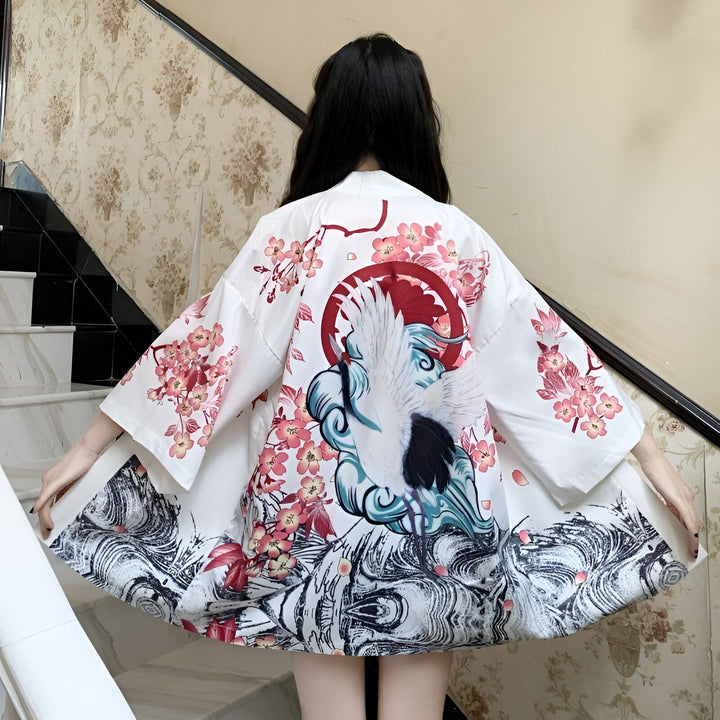 Dos d'une femme portant un kimono blanc avec imprimé de grue et fleurs de cerisier. Vêtements traditionnels japonais. Boutique de kimonos en ligne.