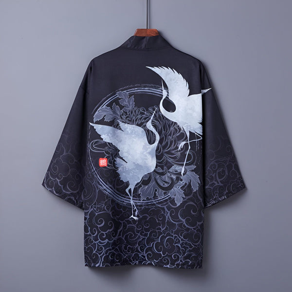 Kimono noir avec motif de grues blanches, suspendu à un cintre. Vêtement japonais traditionnel, idéal pour un style unique et élégant. Découvrez notre collection de kimonos.