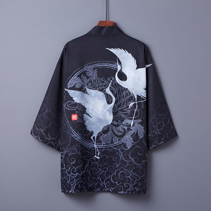 Kimono noir avec motif de grues blanches, suspendu à un cintre. Vêtement japonais traditionnel, idéal pour un style unique et élégant. Découvrez notre collection de kimonos.