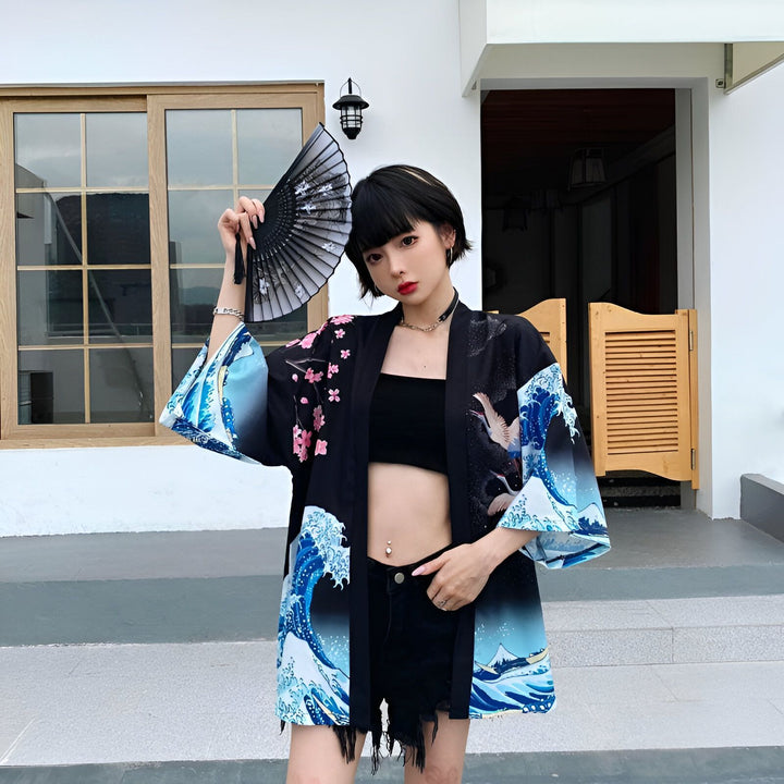 Femme tenant un éventail, portant un kimono noir à motifs de vagues et de fleurs de cerisier. Collection de kimonos, style japonais moderne.