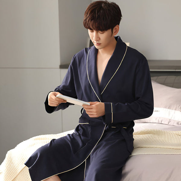 Homme asiatique en kimono bleu marine assis sur un lit, lisant. Vente de kimonos pour hommes.