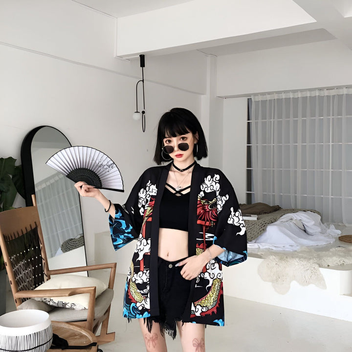 Femme portant un kimono noir avec des motifs de dragons colorés. Elle tient un éventail et porte des lunettes de soleil. Kimonos à la mode disponibles à l'achat. Style japonais moderne.