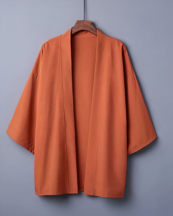 Kimono orange suspendu à un cintre. Vêtements traditionnels japonais, style décontracté et élégant. Idéal pour compléter votre garde-robe avec une touche d'originalité. Découvrez notre collection de kimonos.