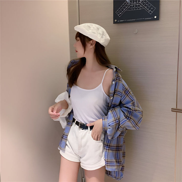 Jeune femme portant une chemise kimono à carreaux bleue et blanche, un débardeur blanc, un short blanc et un béret blanc à fleurs. Vêtements kimono tendance.