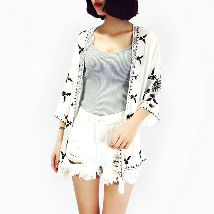 Kimono blanc à motifs noirs, porté par une femme avec un short en jean blanc. Collection de kimonos pour femmes.