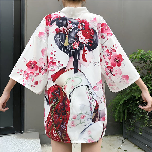 Kimono blanc avec motif de geisha et fleurs de cerisier roses. Vêtements japonais traditionnels en vente.