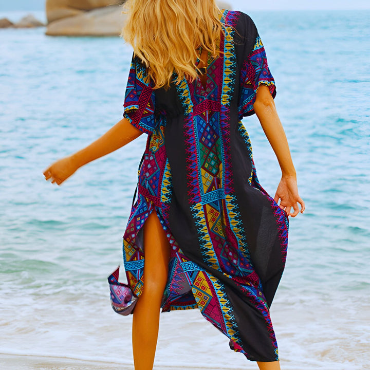 Femme portant un kimono noir à motifs colorés sur une plage tropicale. Vêtements de plage style kimono disponibles à l'achat.