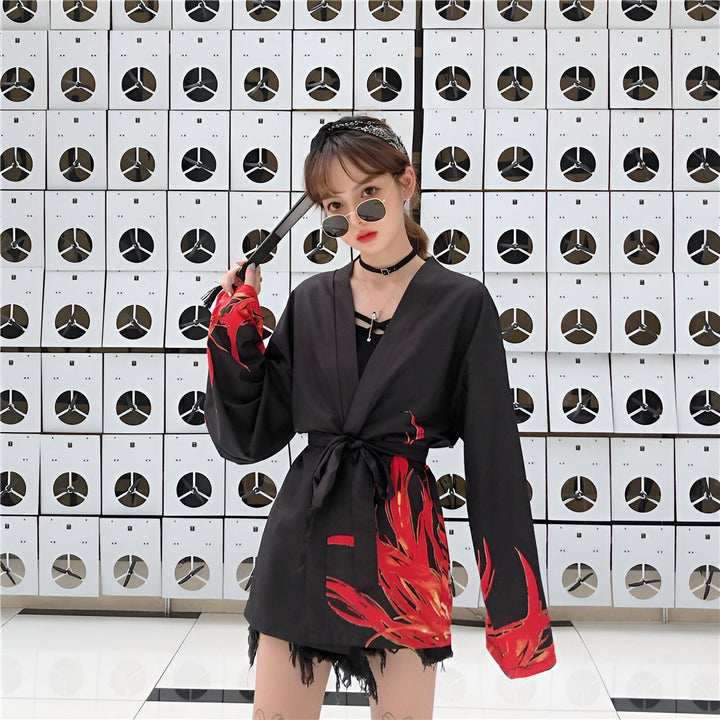 Femme portant un kimono noir avec motifs de flammes rouges. Kimono noué à la taille, style moderne et urbain. Vente de kimonos en ligne.