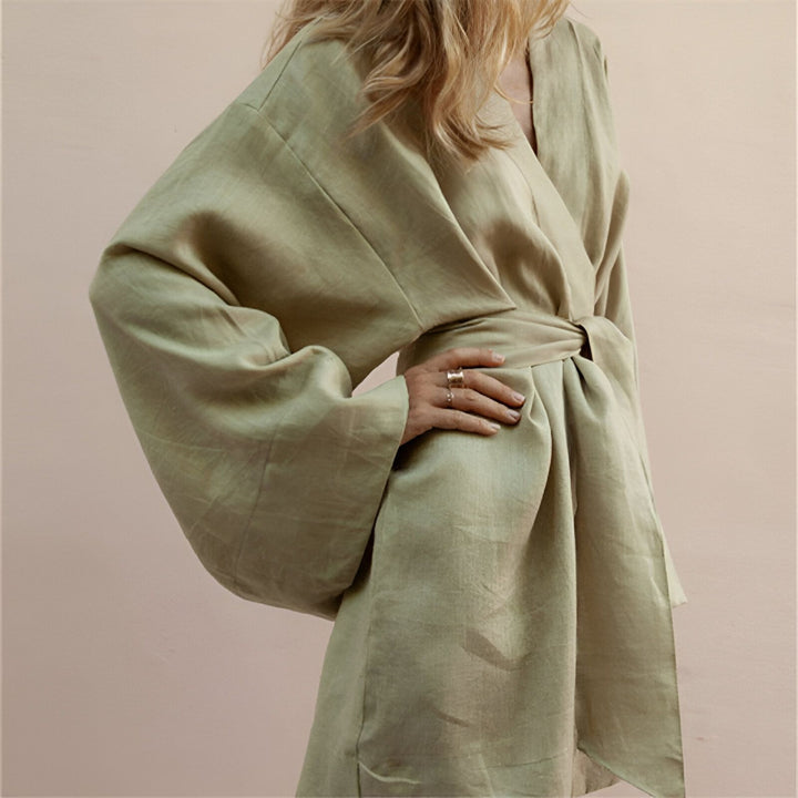 Femme portant un kimono vert clair en lin. Kimono noué à la taille avec une ceinture, manches amples. Vêtements de détente élégants. Boutique de kimonos en ligne.