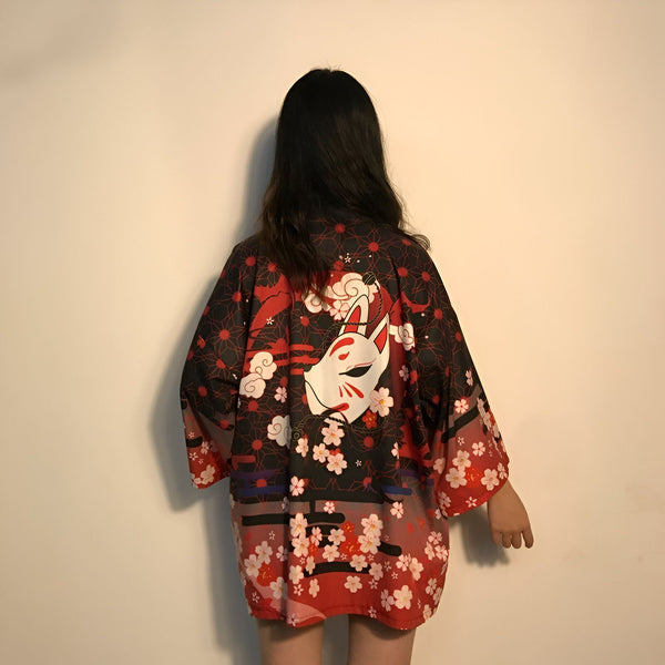 Dos d'une personne portant un kimono noir et rouge à motif de renard et de fleurs de cerisier. Kimono japonais tendance disponible à l'achat.