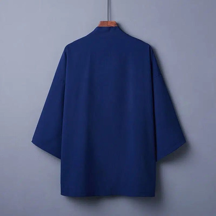 Vue arrière d'un kimono bleu suspendu à un cintre en bois. Vêtement traditionnel japonais avec manches larges et coupe ample. Kimonos en vente.