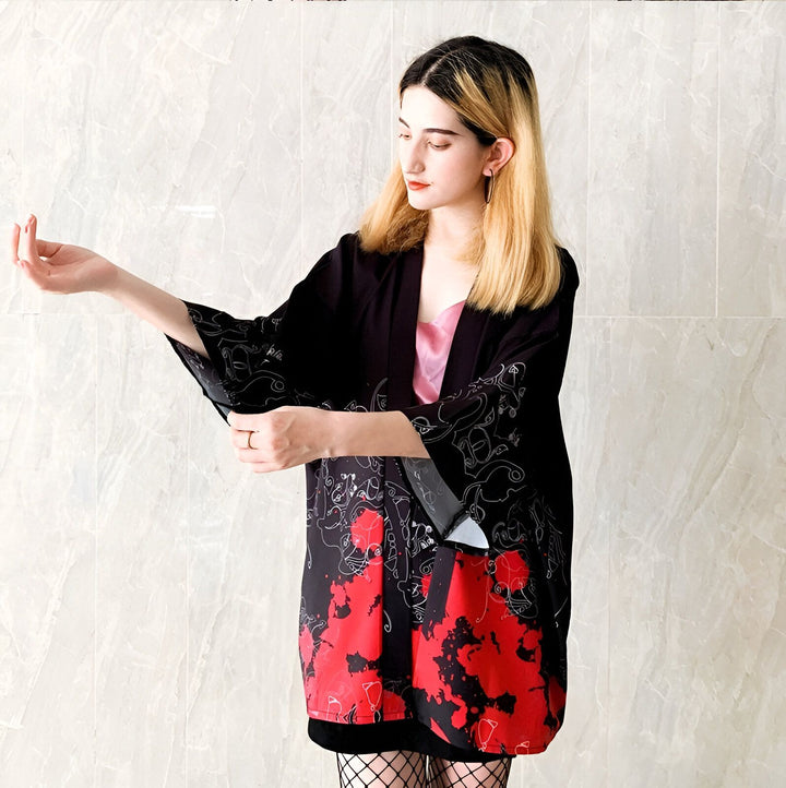 Femme portant un kimono noir avec motifs rouges et blancs. Vêtement japonais traditionnel revisité. Idéal pour un look unique et élégant. Découvrez notre collection de kimonos.