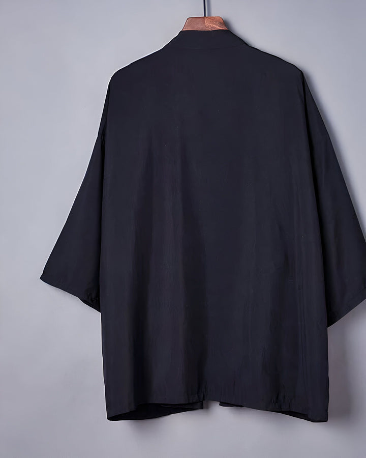 Dos d'un kimono noir suspendu à un cintre. Vêtements de style japonais, amples et confortables. Kimono noir élégant à manches larges. Découvrez notre collection de kimonos uniques.