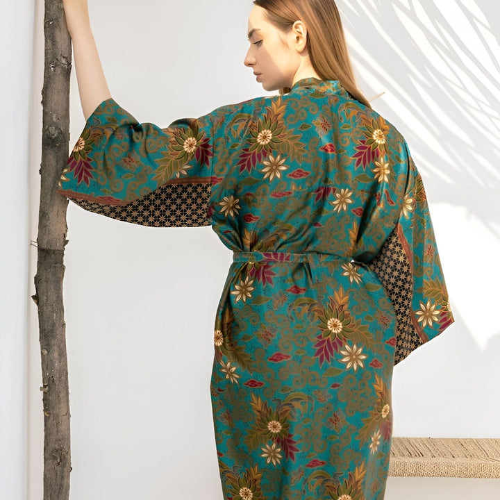 Femme portant un kimono turquoise à motifs floraux. Vêtements de style japonais, peignoir original pour la maison. Mode et confort. Découvrez notre collection unique de kimonos.
