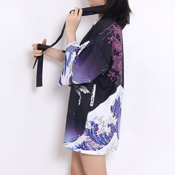 Femme attachant un kimono noir avec motifs de vagues, dragon et poisson. Kimonos pour femmes à vendre.